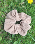 Beige scrunchie on grass with a dandelion in the background